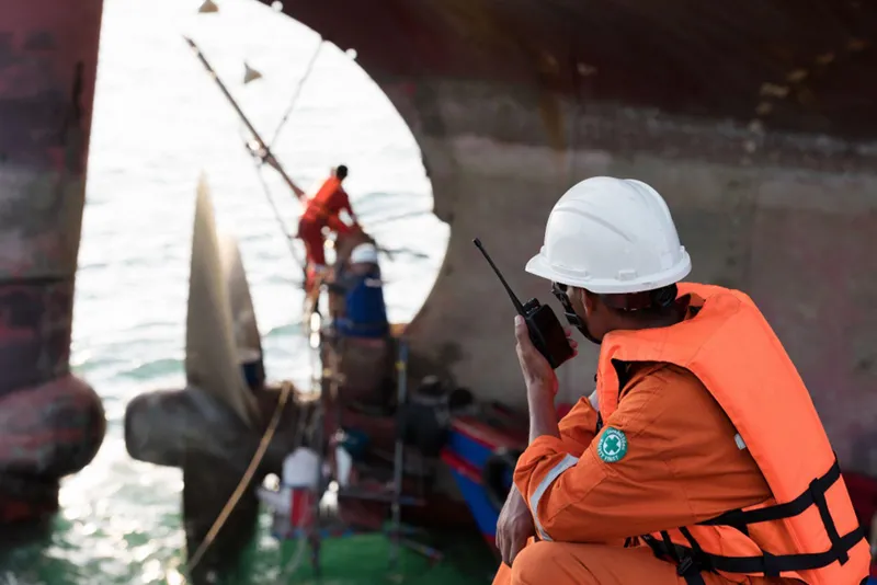 A maritime agent overseeing operations alongside a vessel.
